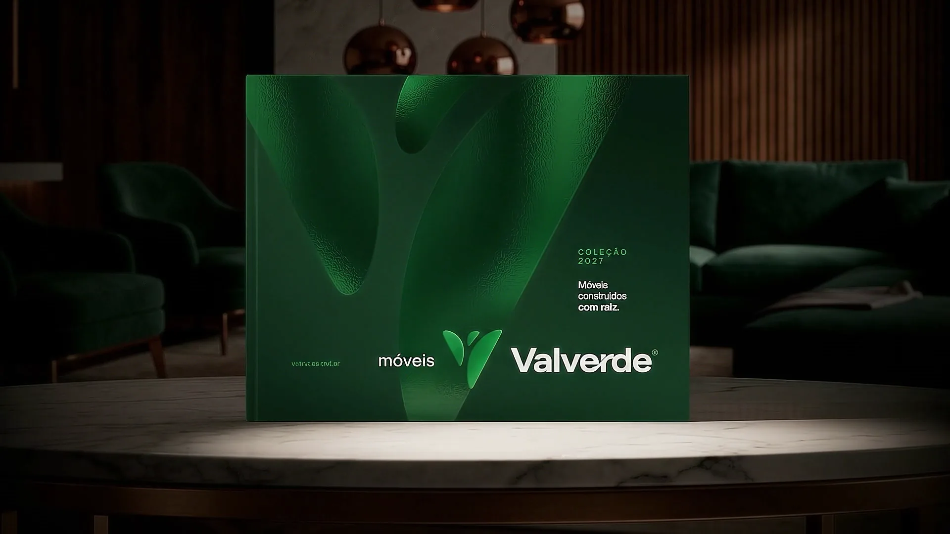 Catálogo Coleção 2027 da Valverde, com capa verde texturizada e o logotipo da marca, iluminado sobre uma mesa de mármore.